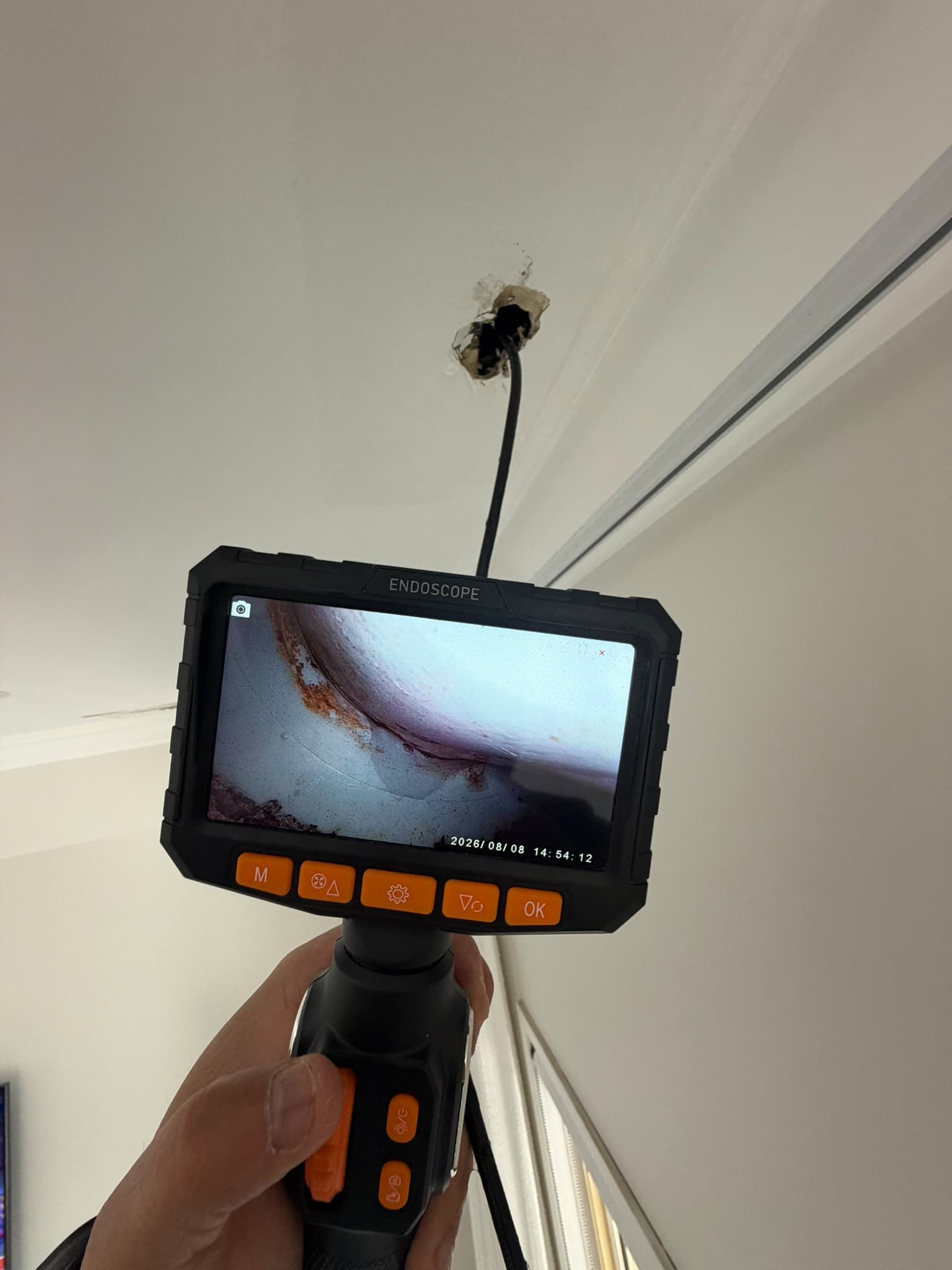 Handheld inspection camera with a probe entering a ceiling cavity
