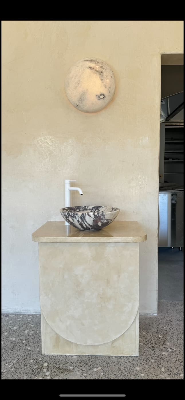 Marbled countertop basin and white mixer on a curved vanity