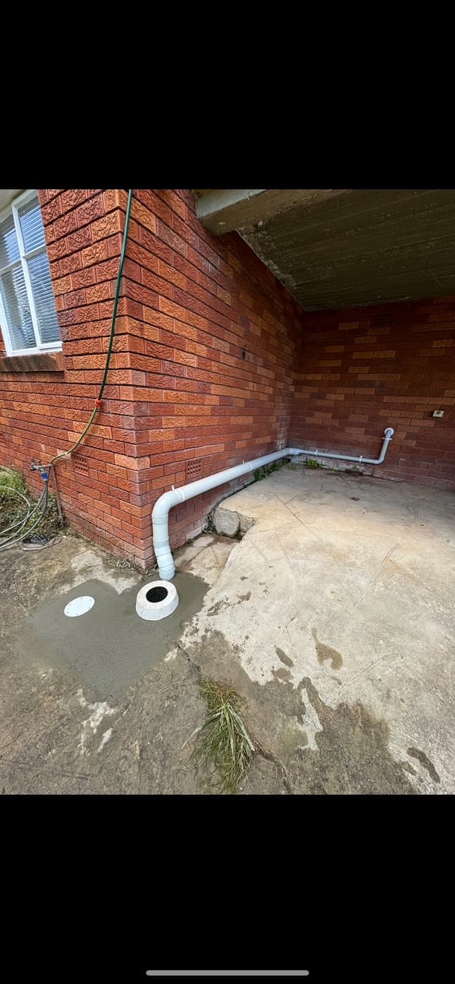 External waste pipework and a grated drain beside a brick wall