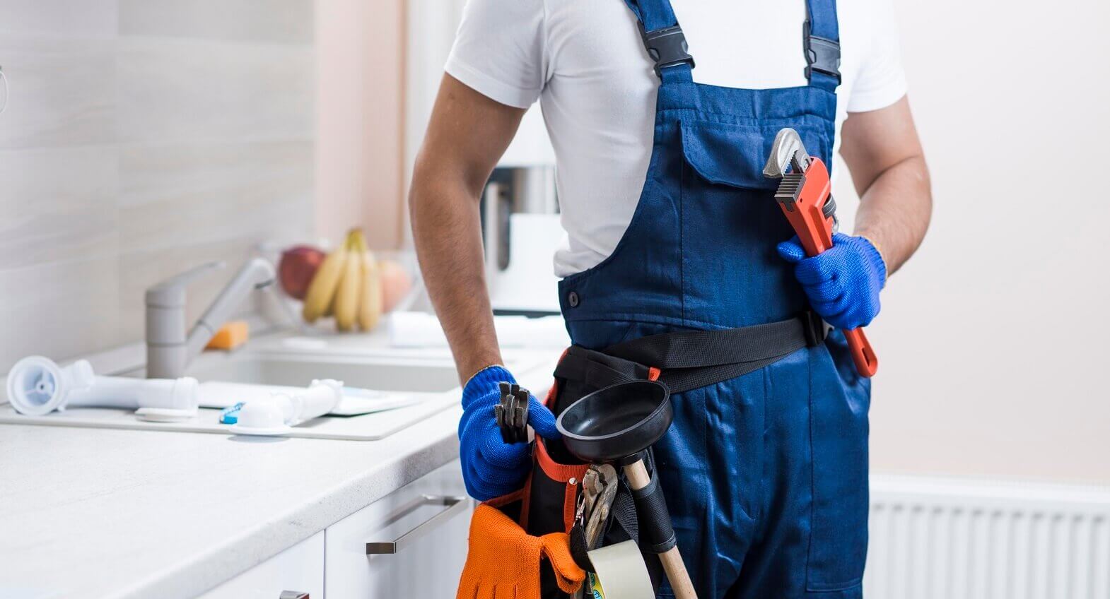 Plumber holding tools in a kitchen