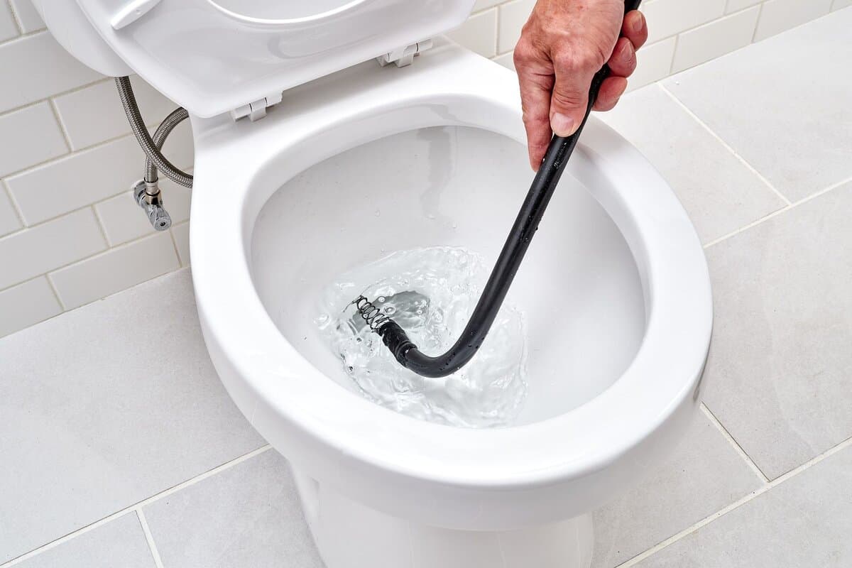 Plumber clearing a blocked toilet in a Glenorie home