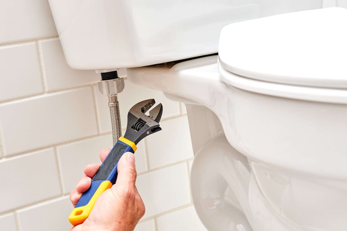 Plumber repairing a leaking toilet in a Revesby bathroom