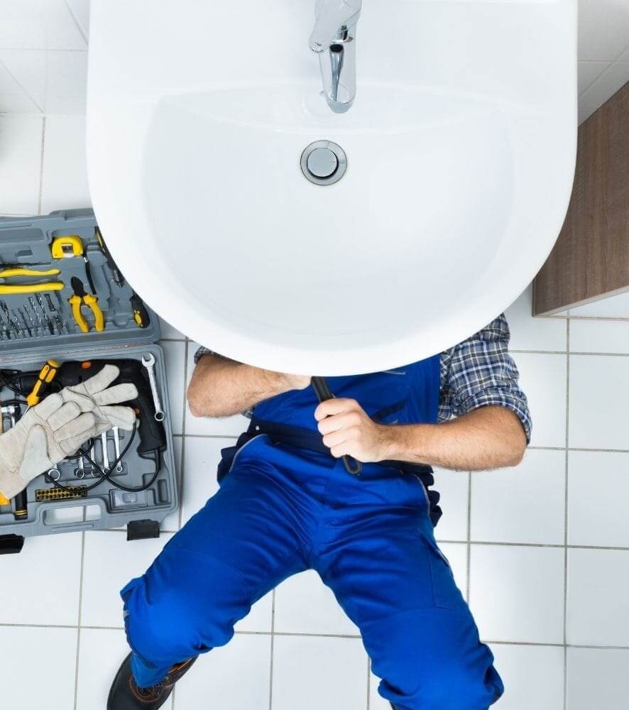 Sydney plumber fixing a leak under the sink